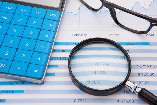 a calculator with blue keys, a pair of glasses, and a magnifying glass on top of a computer printout