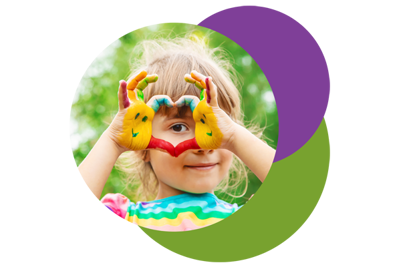 young girl with painted hands making a heart shape with her fingers and peeking through it